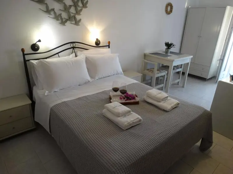 Une chambre lumineuse avec un grand lit recouvert d'une couverture grise et de coussins blancs.