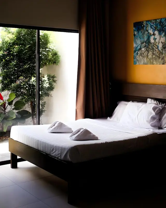 Une chambre lumineuse avec un grand lit et une vue sur la végétation.