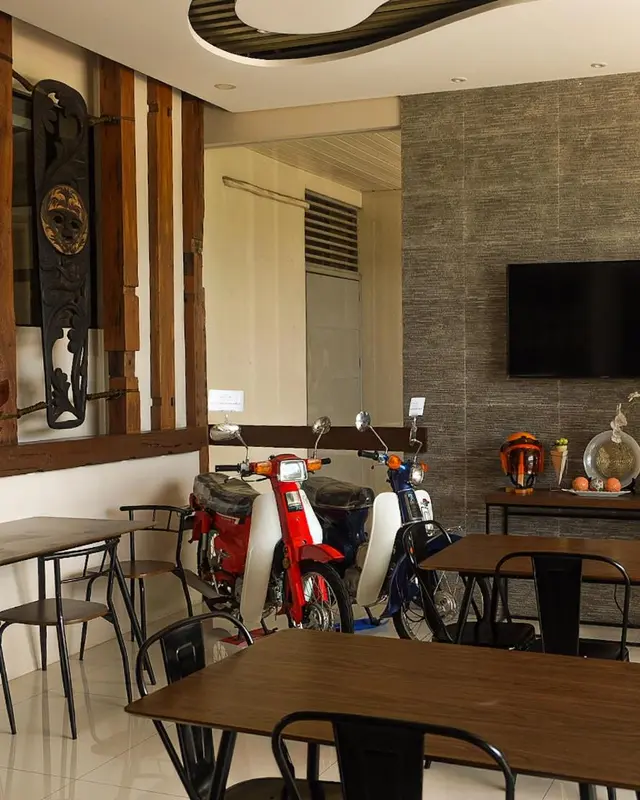 Une salle lumineuse avec des tables, des chaises et des scooters garés.