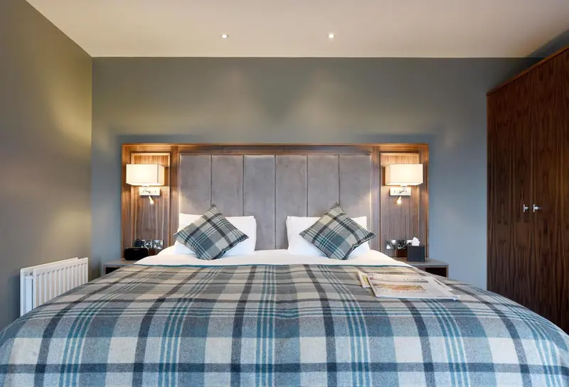 Une chambre avec un grand lit recouvert d'une couverture à carreaux et deux oreillers.