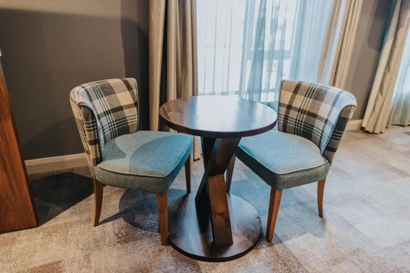 Deux fauteuils et une table ronde se trouvent près d'une fenêtre.