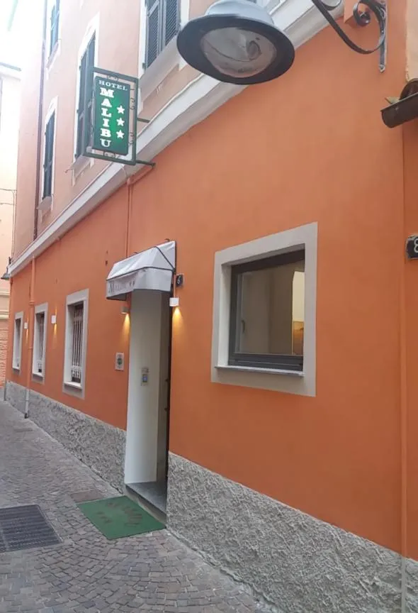 Facade d'un bâtiment orange avec une enseigne d'hôtel et une entrée sombre.