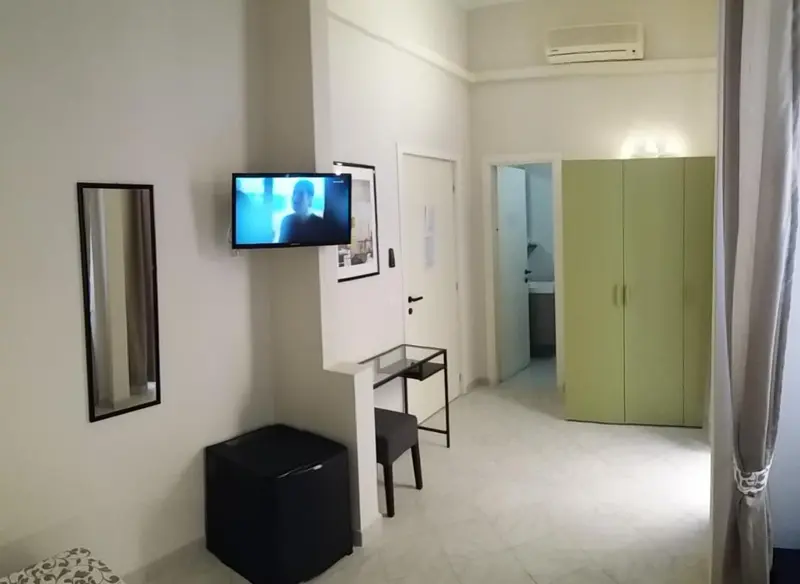 Une télévision murale domine un bureau noir dans une chambre lumineuse.
