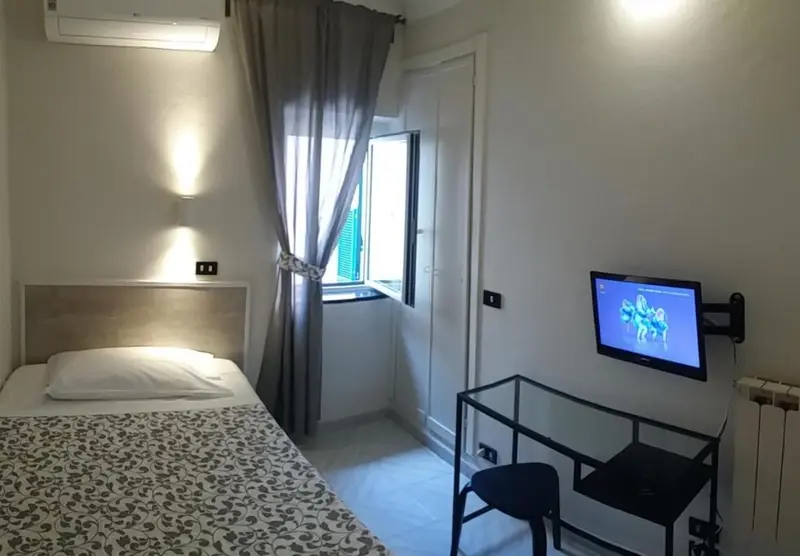 Une chambre lumineuse avec un lit simple et un téléviseur fixé au mur.