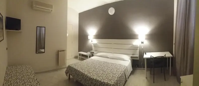 Une chambre lumineuse avec un grand lit et un bureau.