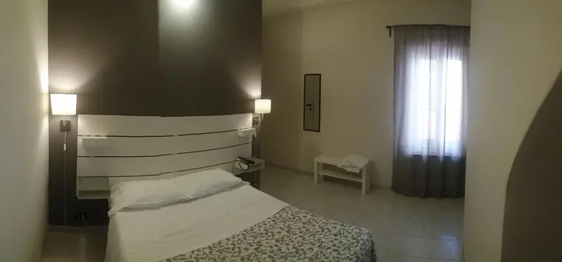 Une chambre lumineuse avec un grand lit et des rideaux blancs.