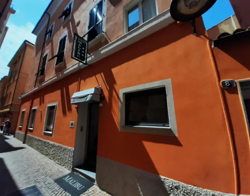 Façade d'un bâtiment orange à fenêtres rectangulaires et balcon.