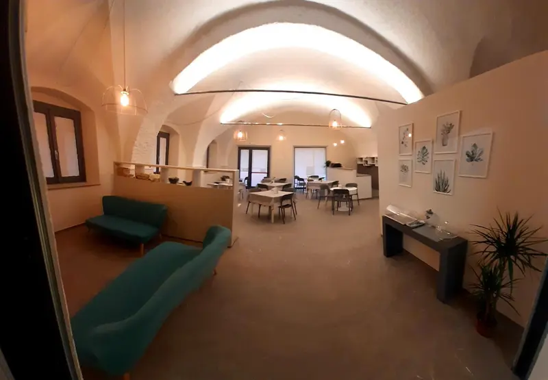 Une salle lumineuse avec des tables et des canapés verts.