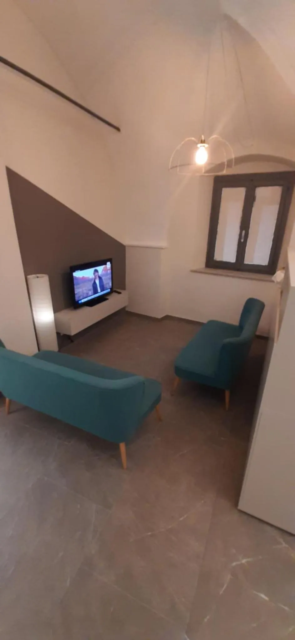 Un espace de détente avec canapés verts et une télévision murale.
