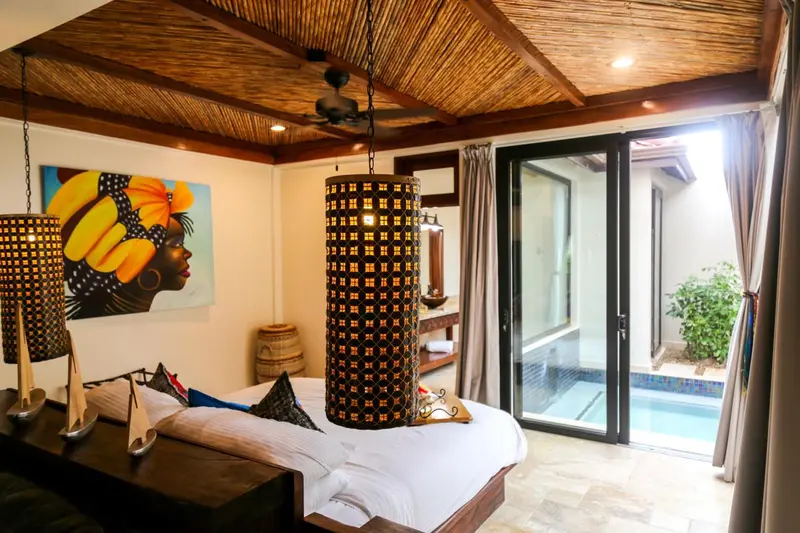 Une chambre lumineuse avec un grand lit et un accès à une piscine extérieure.