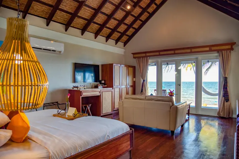 Une chambre lumineuse avec un lit, un canapé et une vue sur la mer.