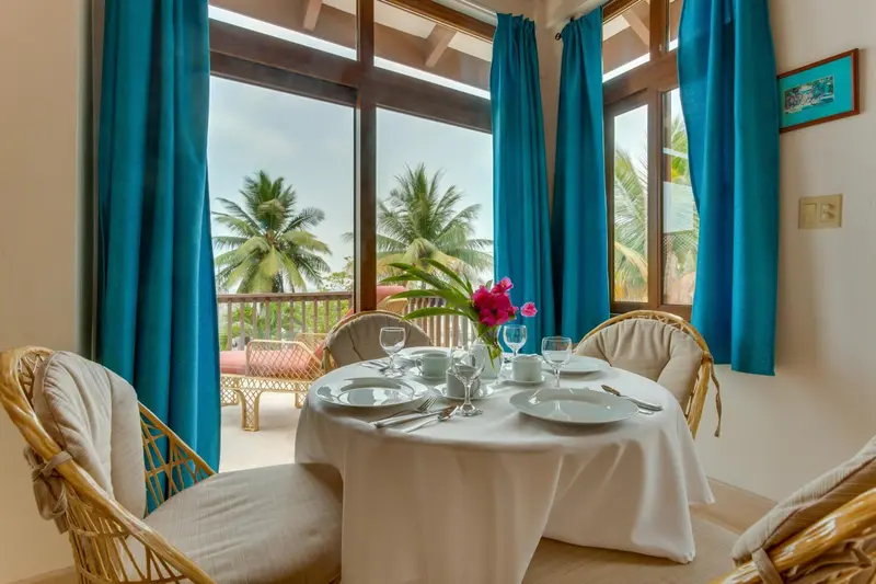 Table ronde dressée avec de la vaisselle sur une terrasse ensoleillée.