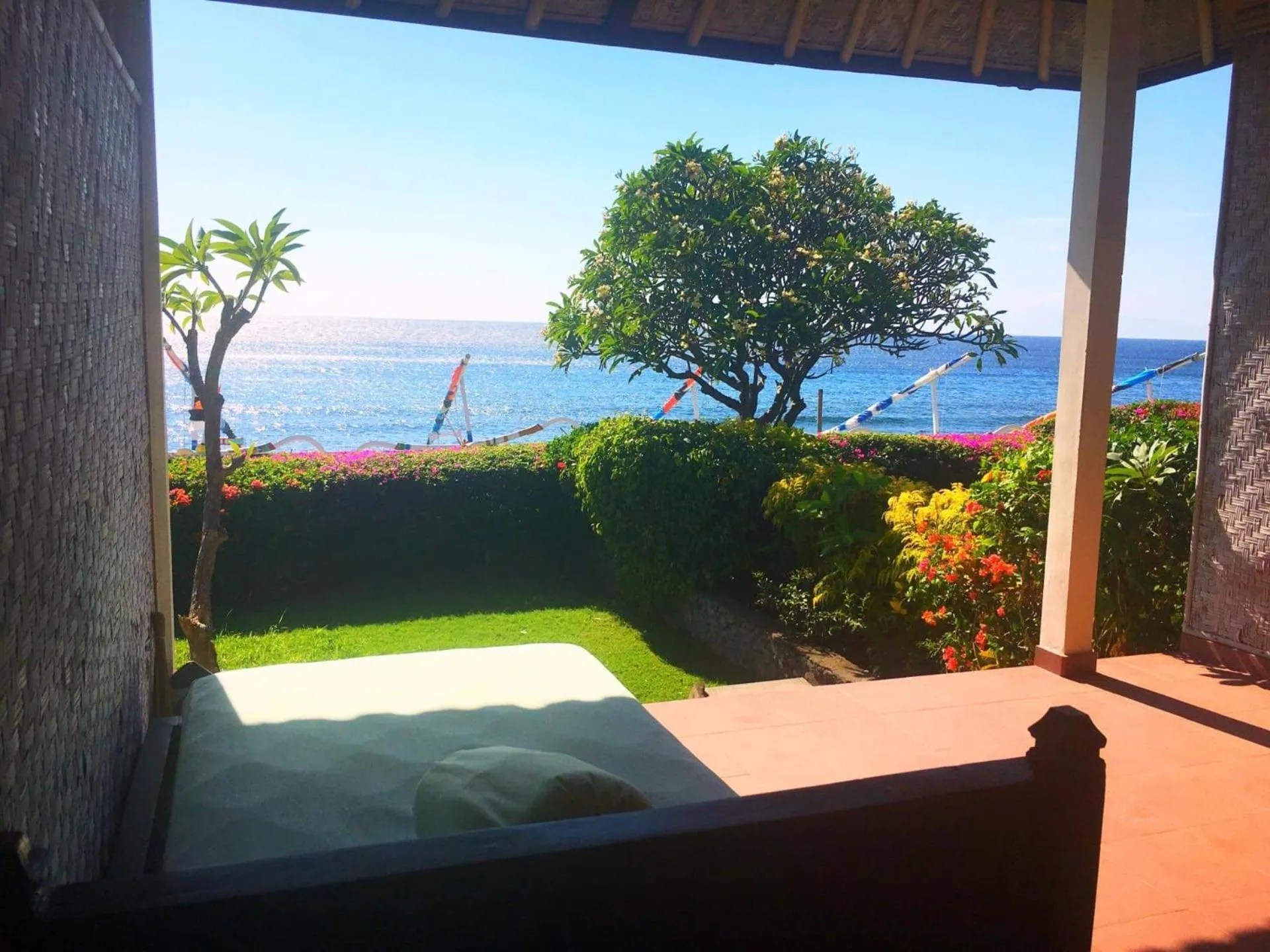 Vue sur la mer depuis une terrasse ombragée.