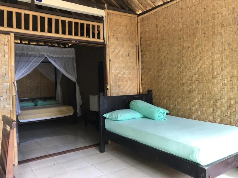 Une chambre avec deux lits simples et une moustiquaire.