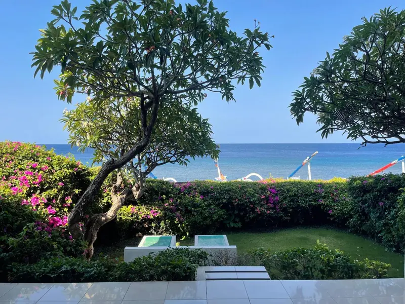 Jardin verdoyant surplombant la mer bleue et une plage.