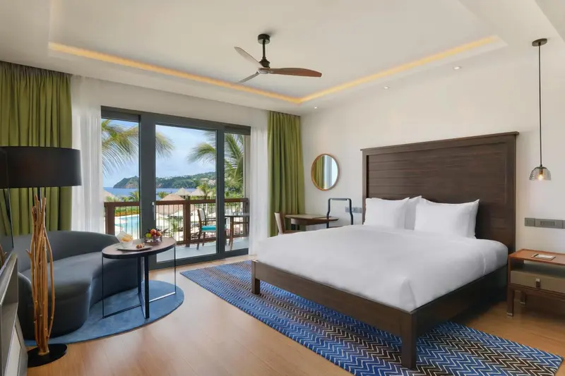 Chambre lumineuse avec un grand lit et une vue sur la mer.