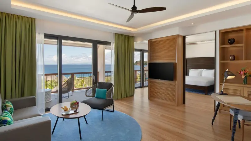 Espace de vie lumineux avec canapé, table basse et accès à un balcon avec vue sur la mer.