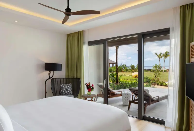 Une chambre lumineuse s'ouvre sur une terrasse avec vue sur la végétation.