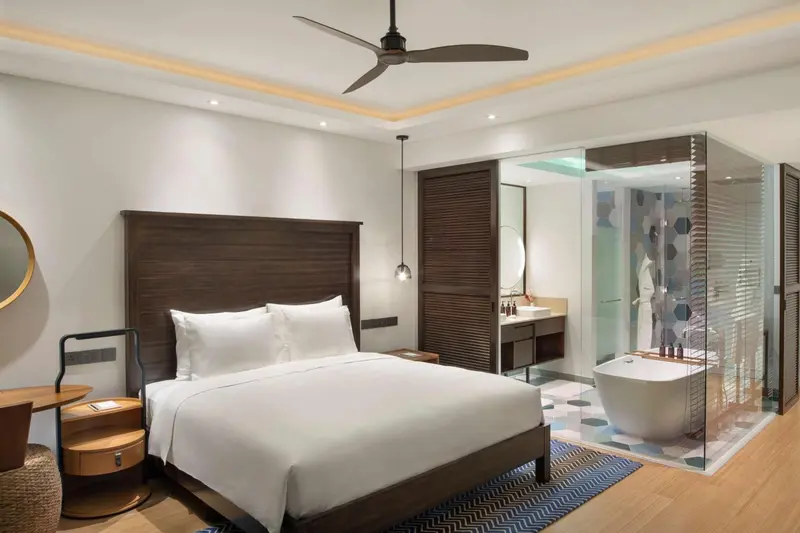 Une chambre lumineuse avec un grand lit et une salle de bain ouverte.