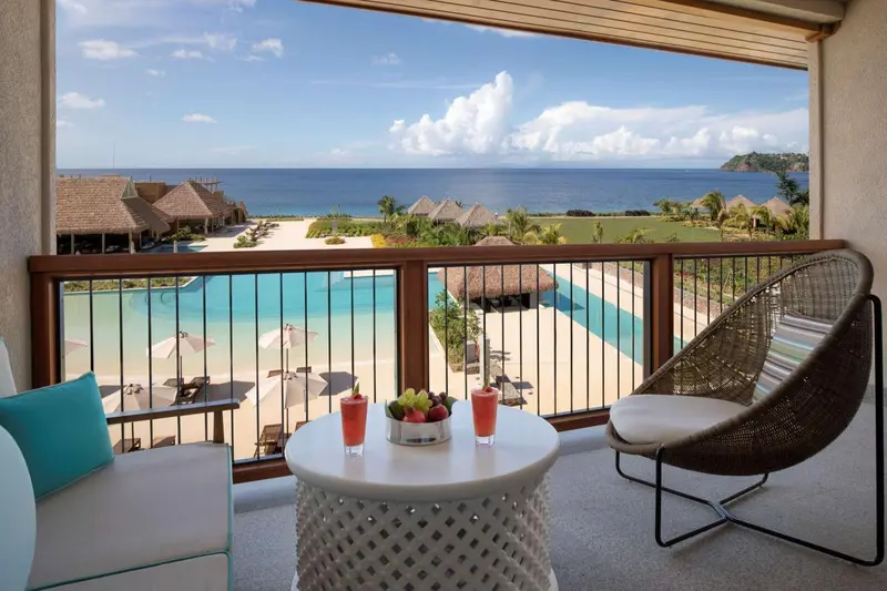Terrasse avec table basse et vue sur une piscine et la mer.