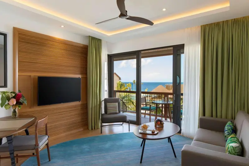 Espace de vie lumineux avec canapé, fauteuil et vue sur la mer.