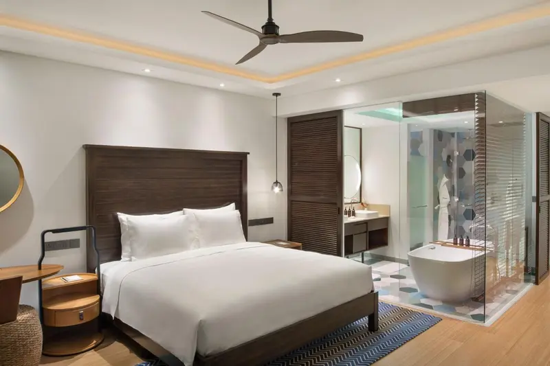 Une chambre lumineuse avec un grand lit et une salle de bain ouverte.