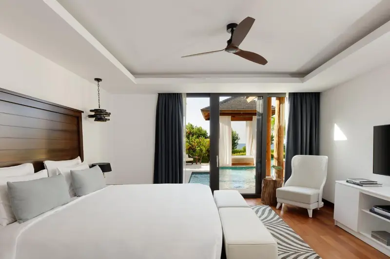 Une chambre lumineuse avec un grand lit et un accès à une piscine.