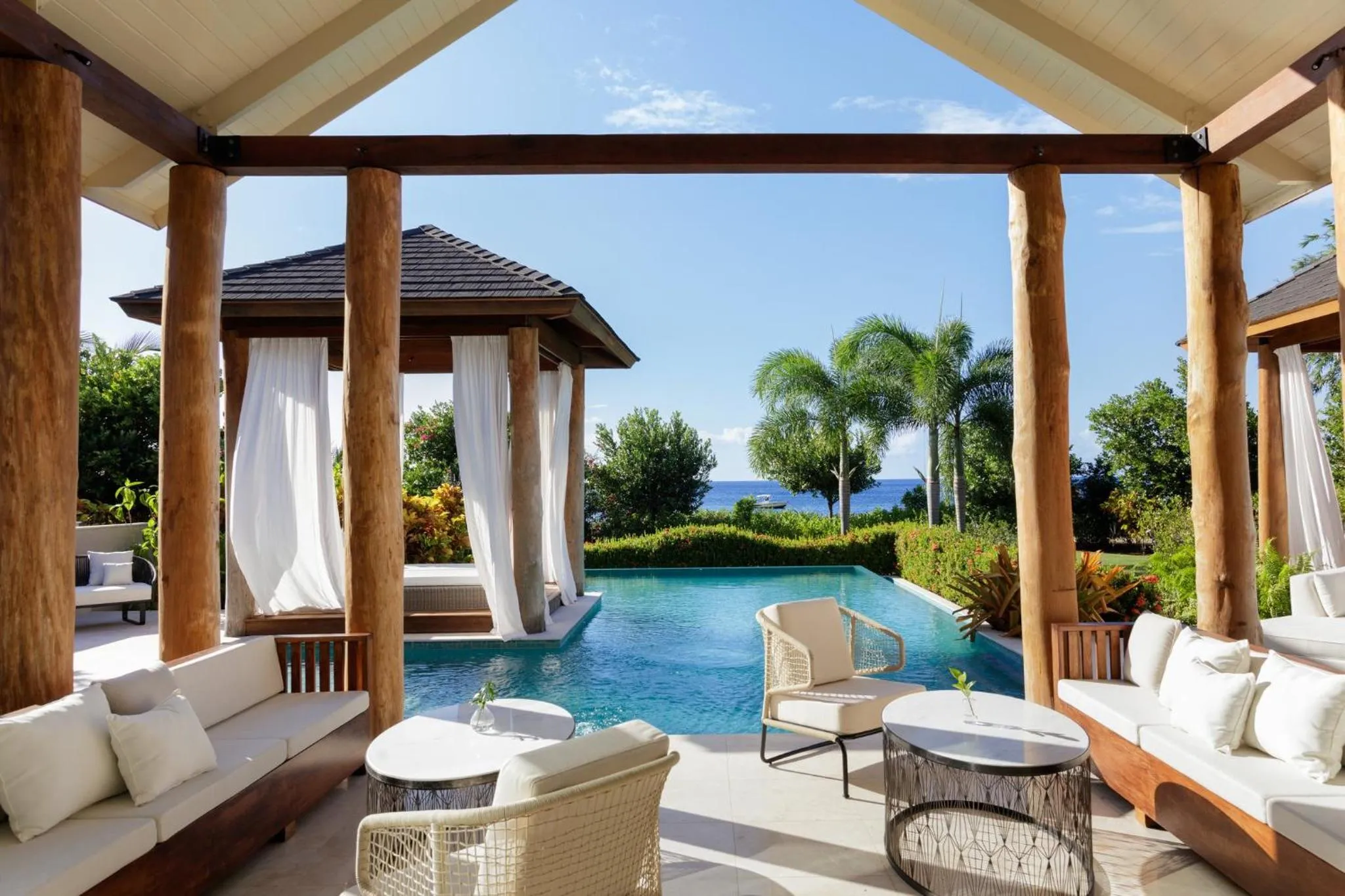 Espace de détente extérieur avec canapés et piscine face à la mer.
