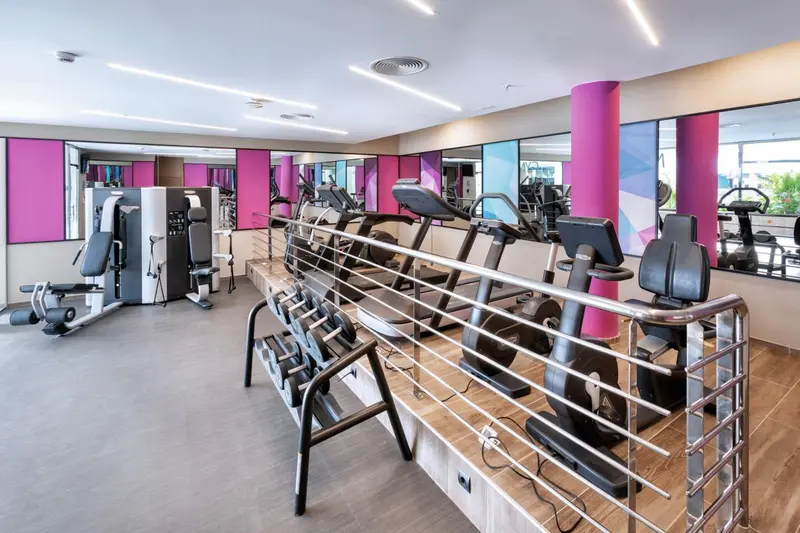Une salle de sport lumineuse avec des équipements de fitness et des miroirs.
