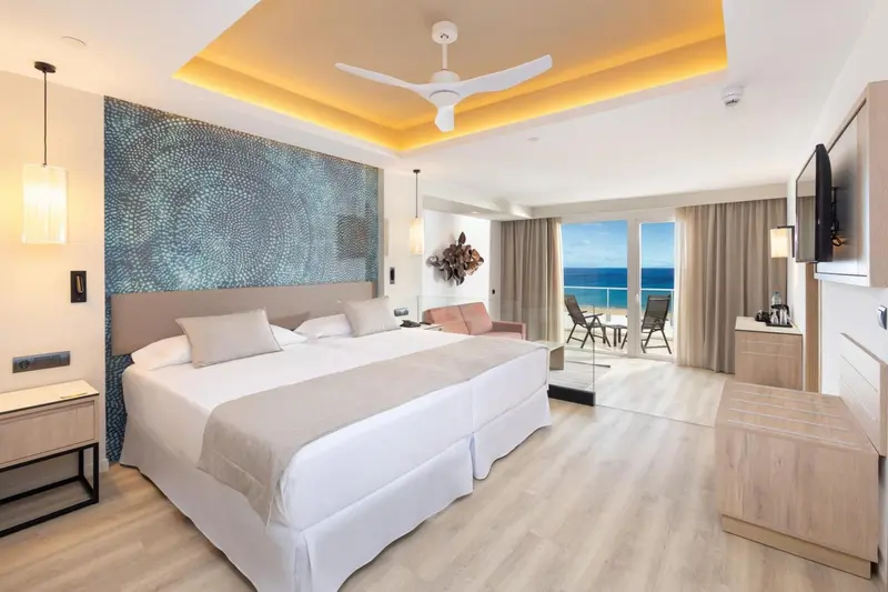 Une chambre lumineuse avec un grand lit et une vue sur la mer.