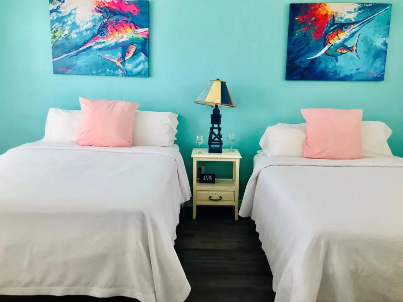 Deux lits simples avec des oreillers roses dans une chambre lumineuse.