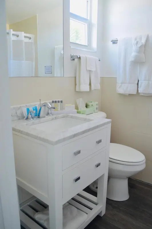 Une salle de bain lumineuse avec lavabo, miroir et douche.
