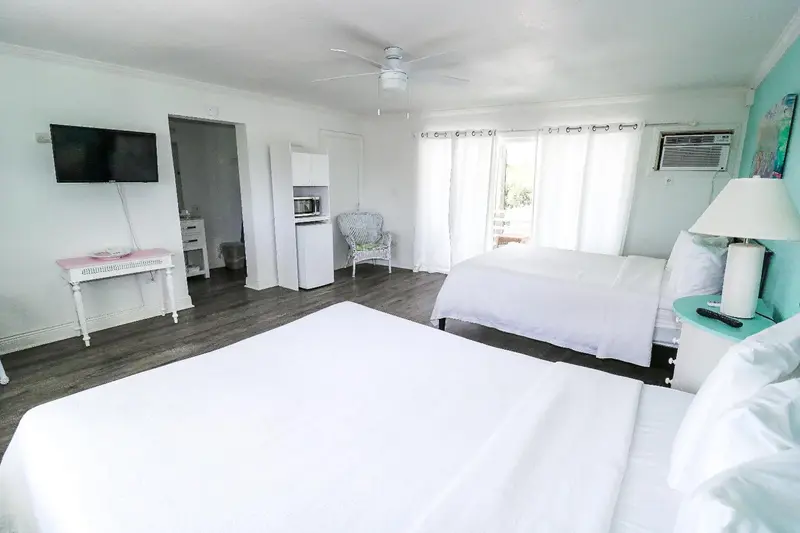 Une chambre lumineuse avec deux lits blancs et un bureau.