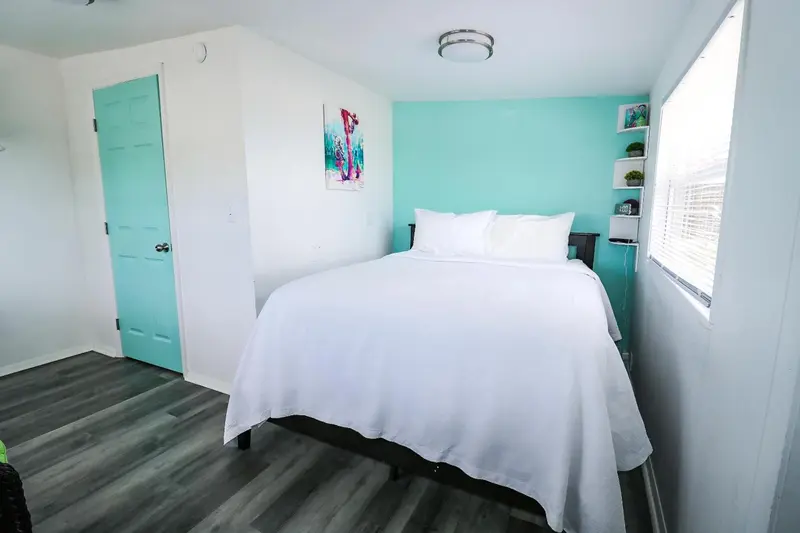 Une chambre lumineuse avec un lit recouvert d'une courtepointe blanche.