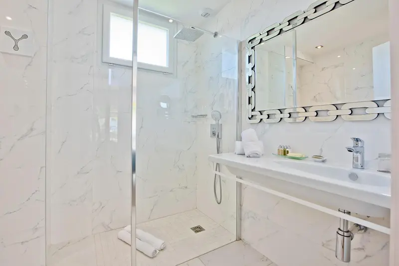 Une salle de bain moderne avec douche à l'italienne et vasque blanche.