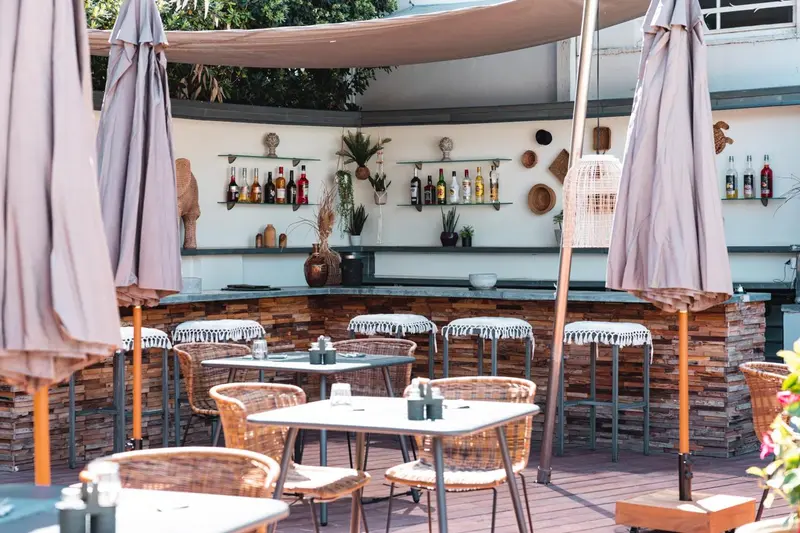 Terrasse ombragée avec un bar et des tables à manger.