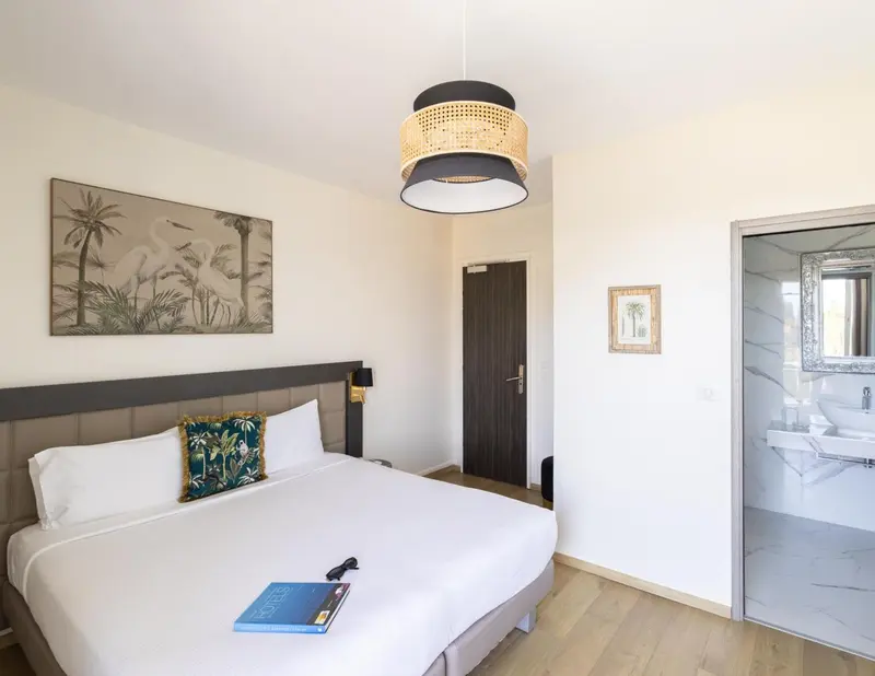 Une chambre lumineuse avec un grand lit et un décor tropical.