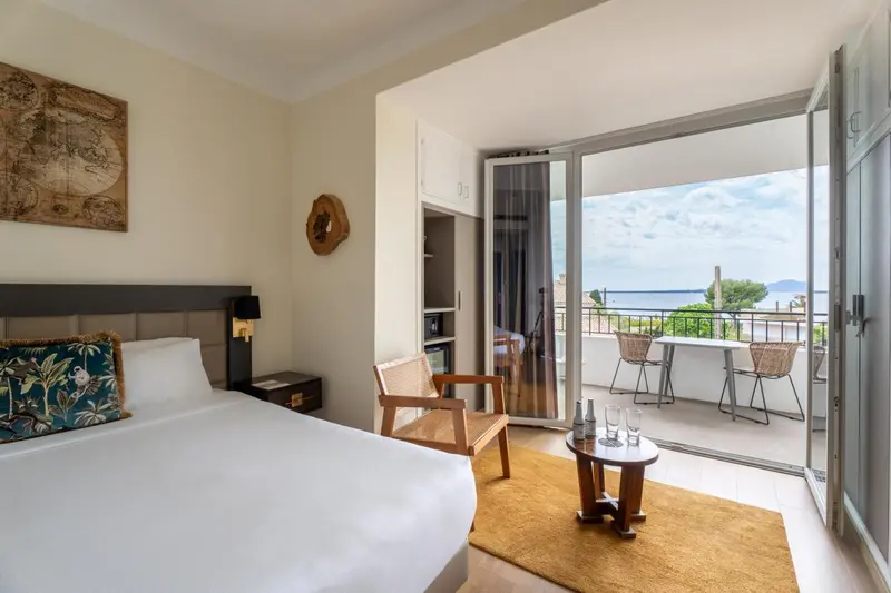 Une chambre lumineuse s'ouvre sur une terrasse avec vue sur la mer.