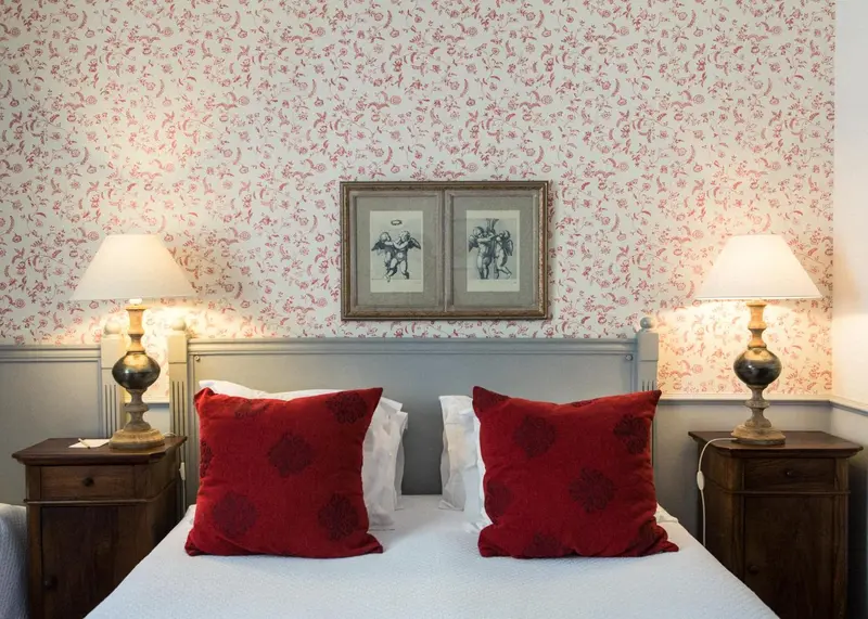 Un lit avec des oreillers rouges et des lampes de chevet sur des tables de nuit.