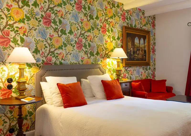 Une chambre à coucher lumineuse avec un lit recouvert d'une courtepointe blanche et de coussins colorés.