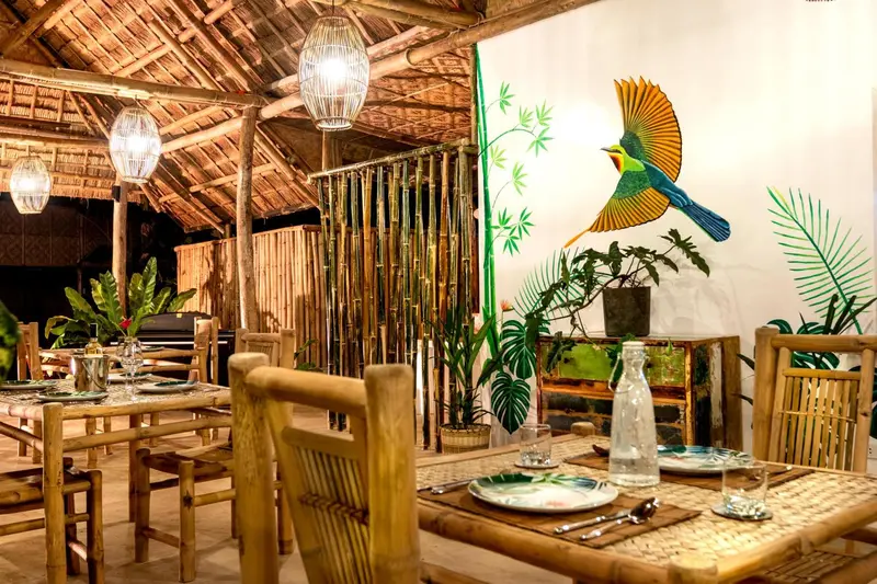 Une salle à manger en bois avec des tables dressées et une décoration tropicale.