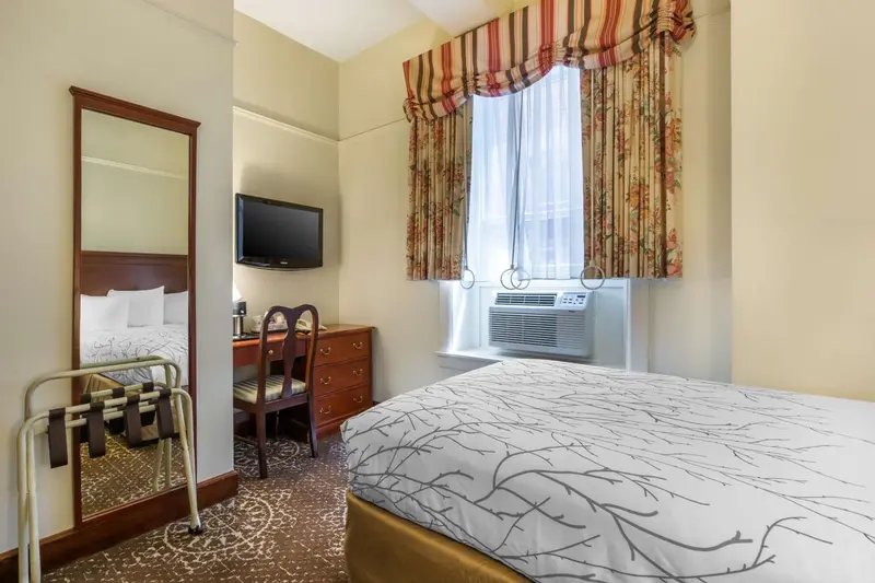 Une chambre d'hôtel lumineuse avec un lit et un bureau près d'une fenêtre.