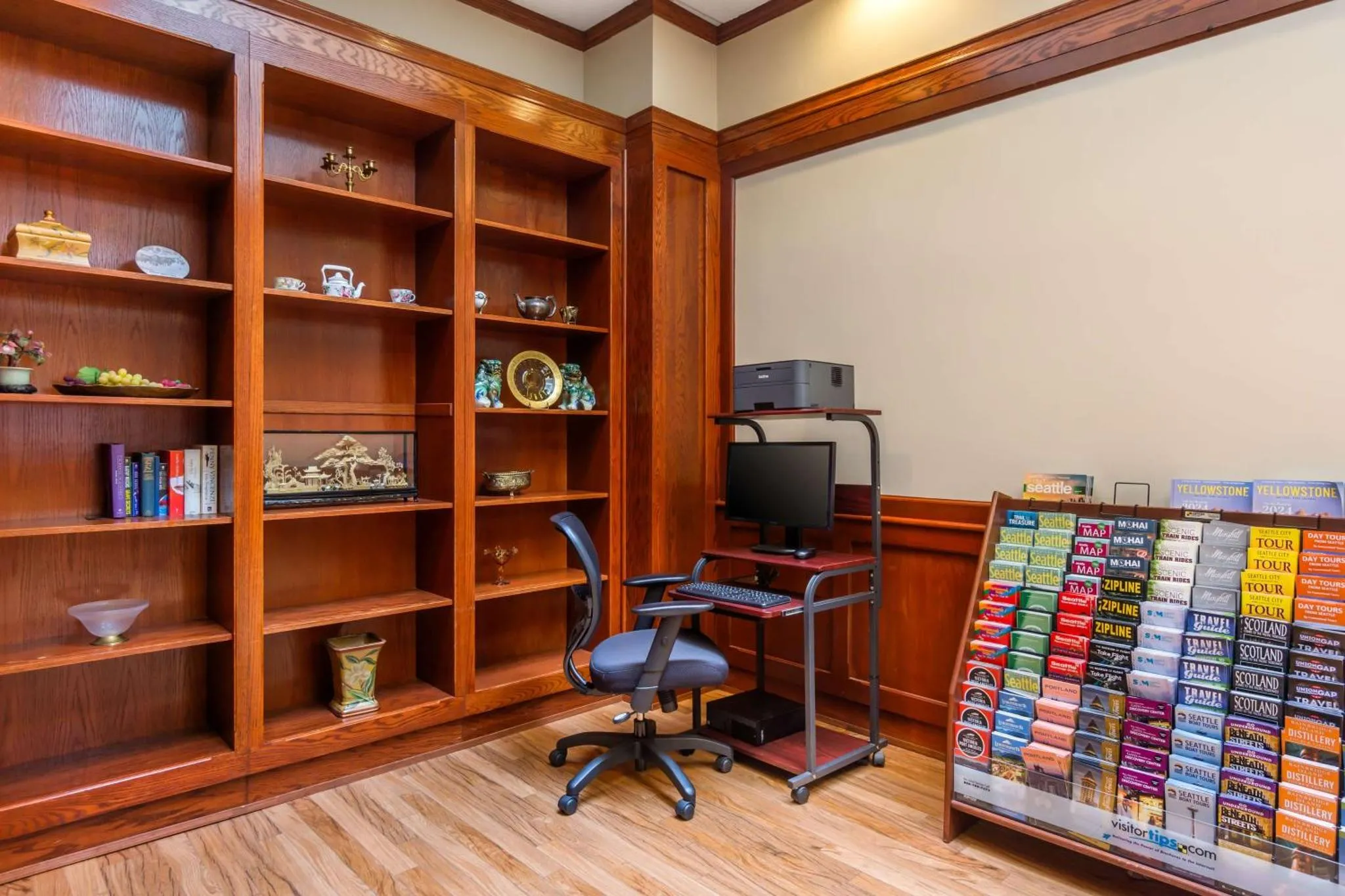 Bibliothèque en bois avec des étagères remplies d'objets décoratifs et un bureau avec un ordinateur.