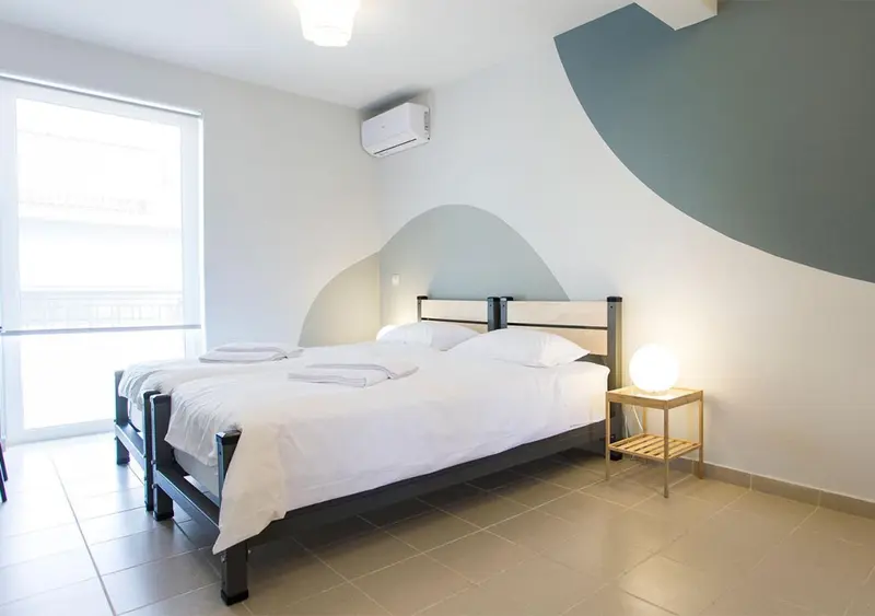 Une chambre lumineuse avec un grand lit et une décoration murale graphique.
