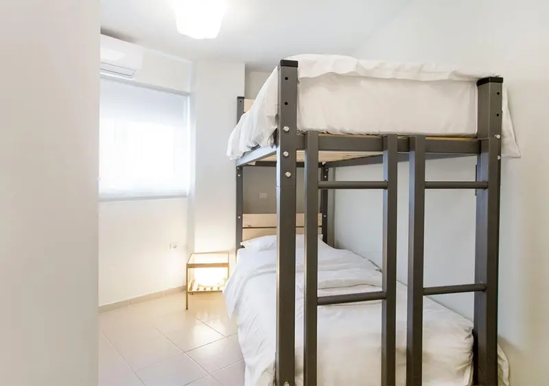 Une chambre avec un lit superposé et une table de chevet.
