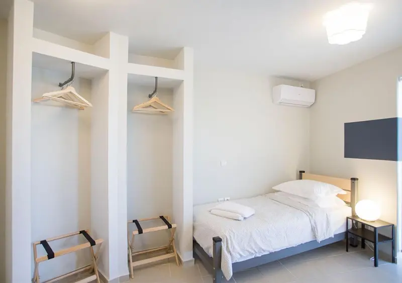 Une chambre lumineuse avec un lit simple et des étagères ouvertes.