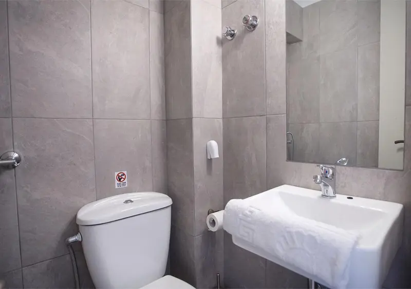 Une salle de bain moderne avec des carreaux gris et des sanitaires blancs.