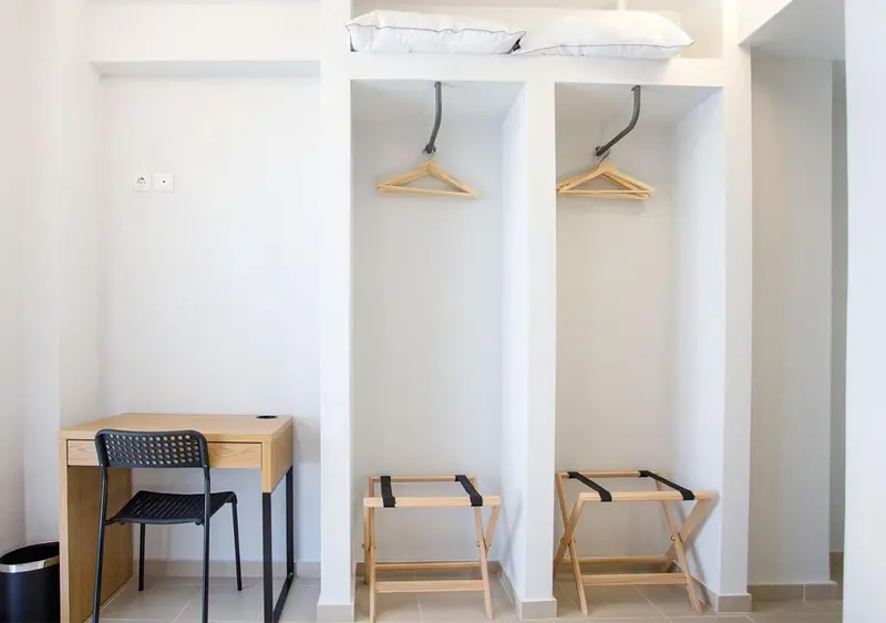 Une chambre lumineuse avec un bureau et des patères.