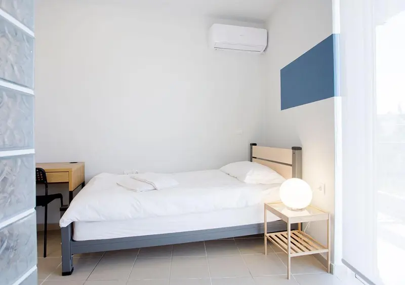 Une chambre lumineuse avec un lit simple et une table de chevet.