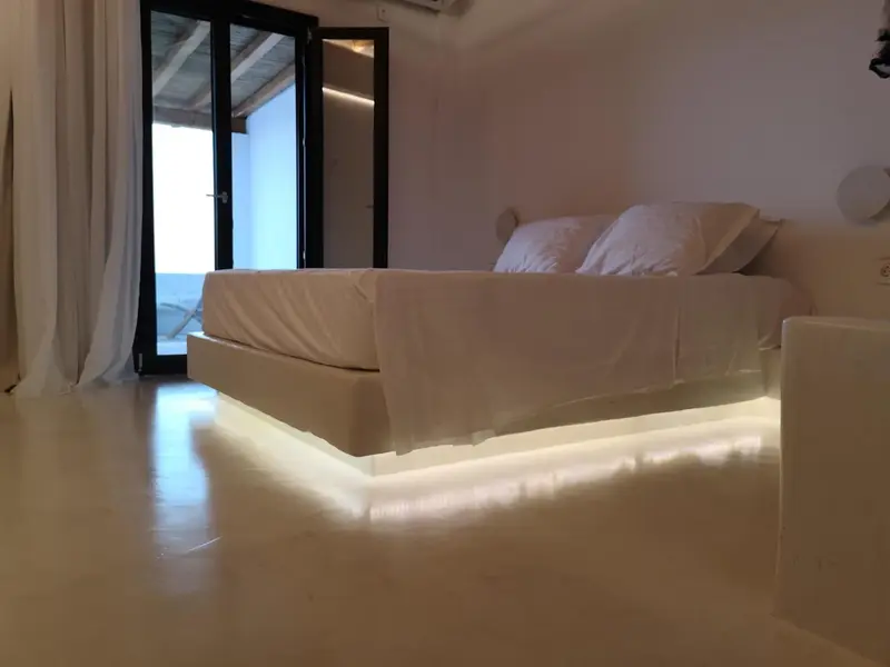 Une chambre lumineuse avec un grand lit blanc et un accès à une terrasse.